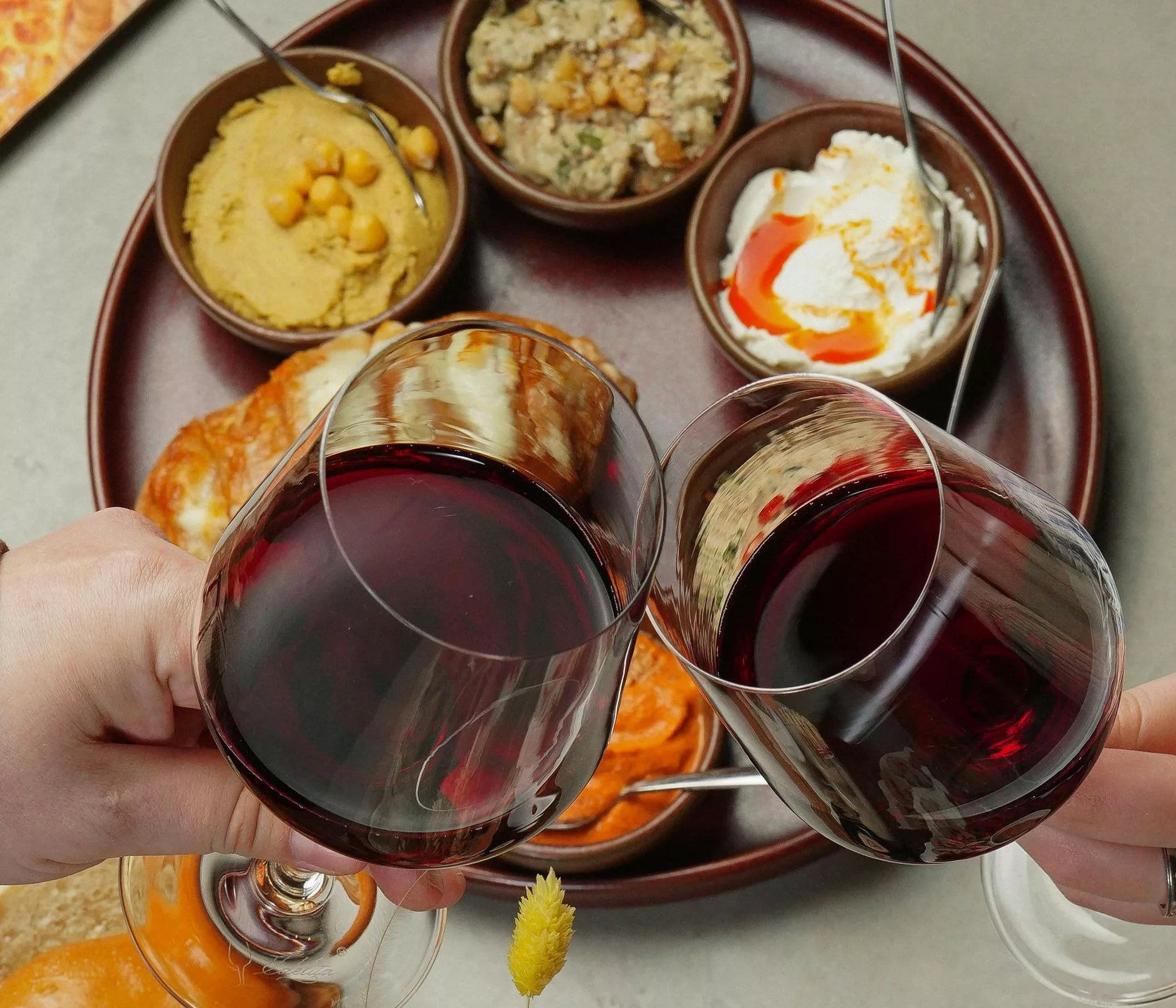 deux verres de vin rouge, accompagnés d'un menu de style mezzé